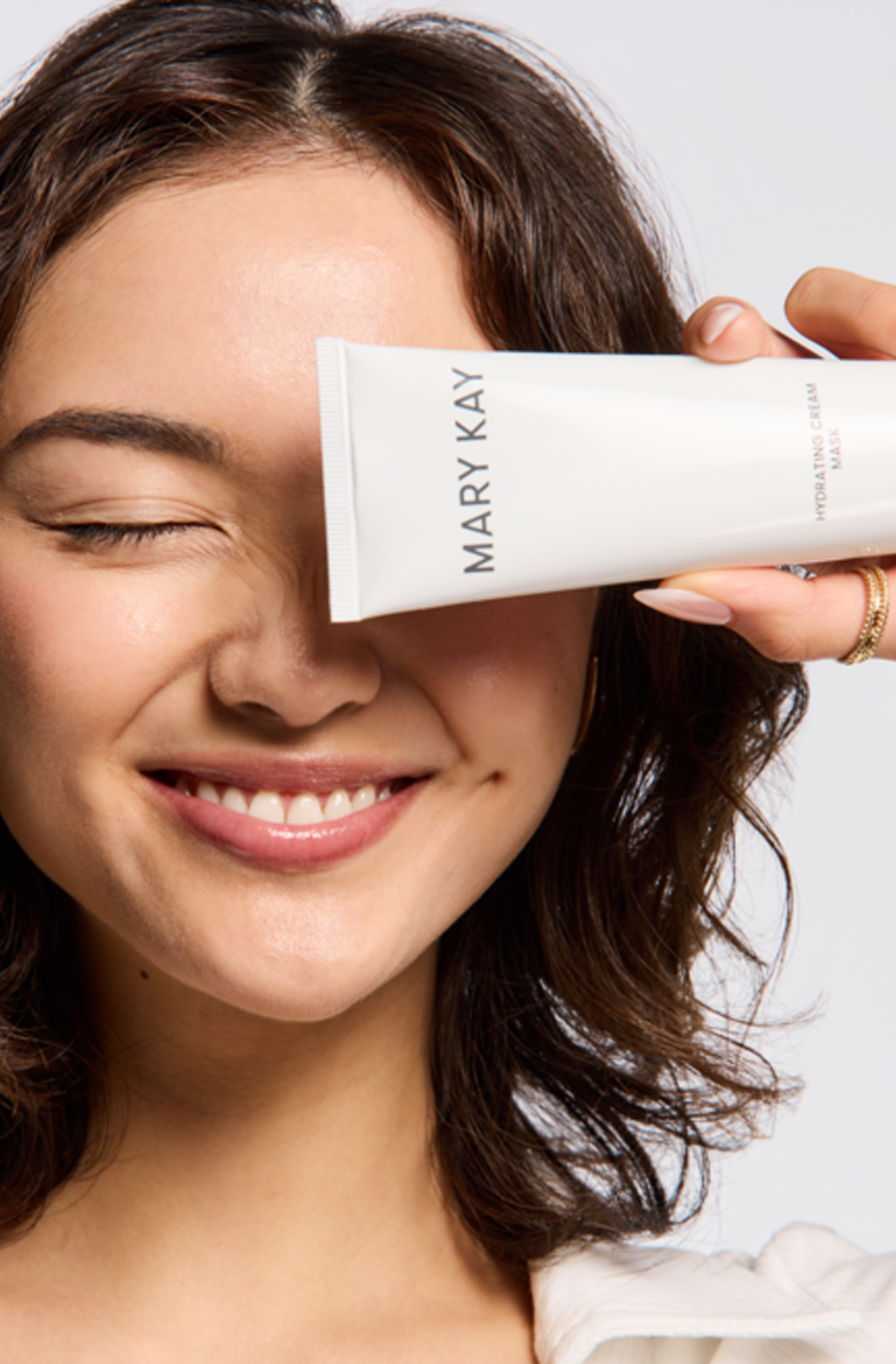  Close-up of person holding Mary Kay hydrating cream mask near face during skincare routine for smooth, radiant skin.